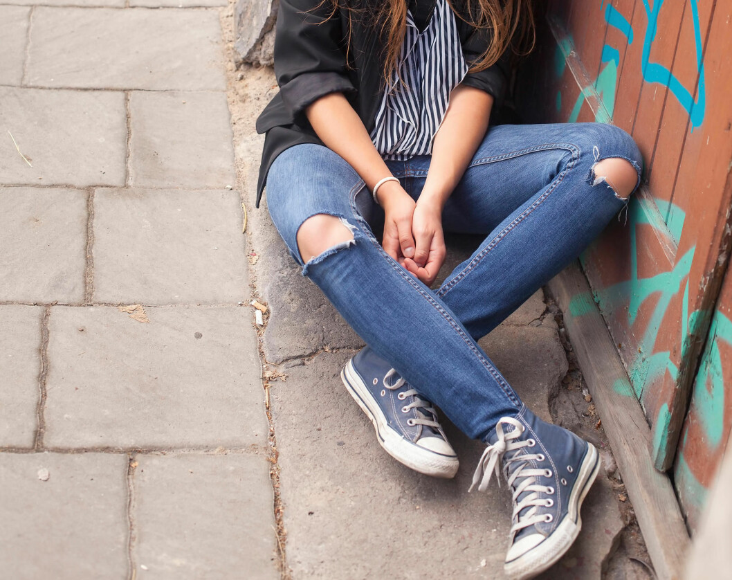 Young hipster girl sitting on the street.