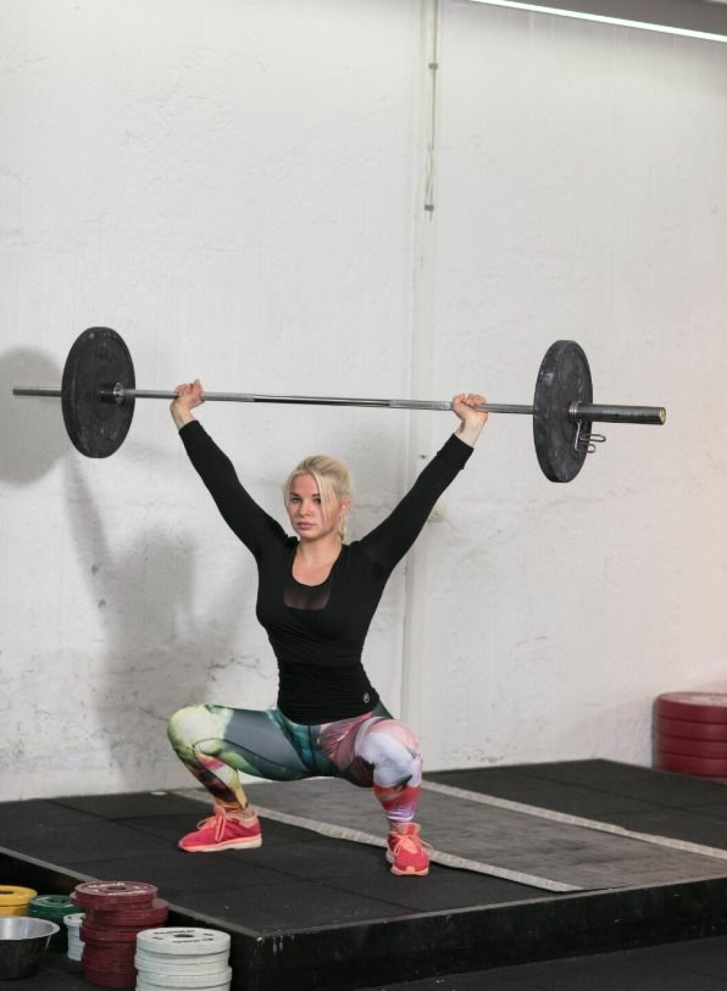 <strong>B. Tänk att du ska hålla ganska brett, och krama stången hårt med dina händer. Gå ned i en djup squat, var noga med att pressa fötter och knän lätt utåt i rörelsen – knäna får inte falla in.<br></strong>