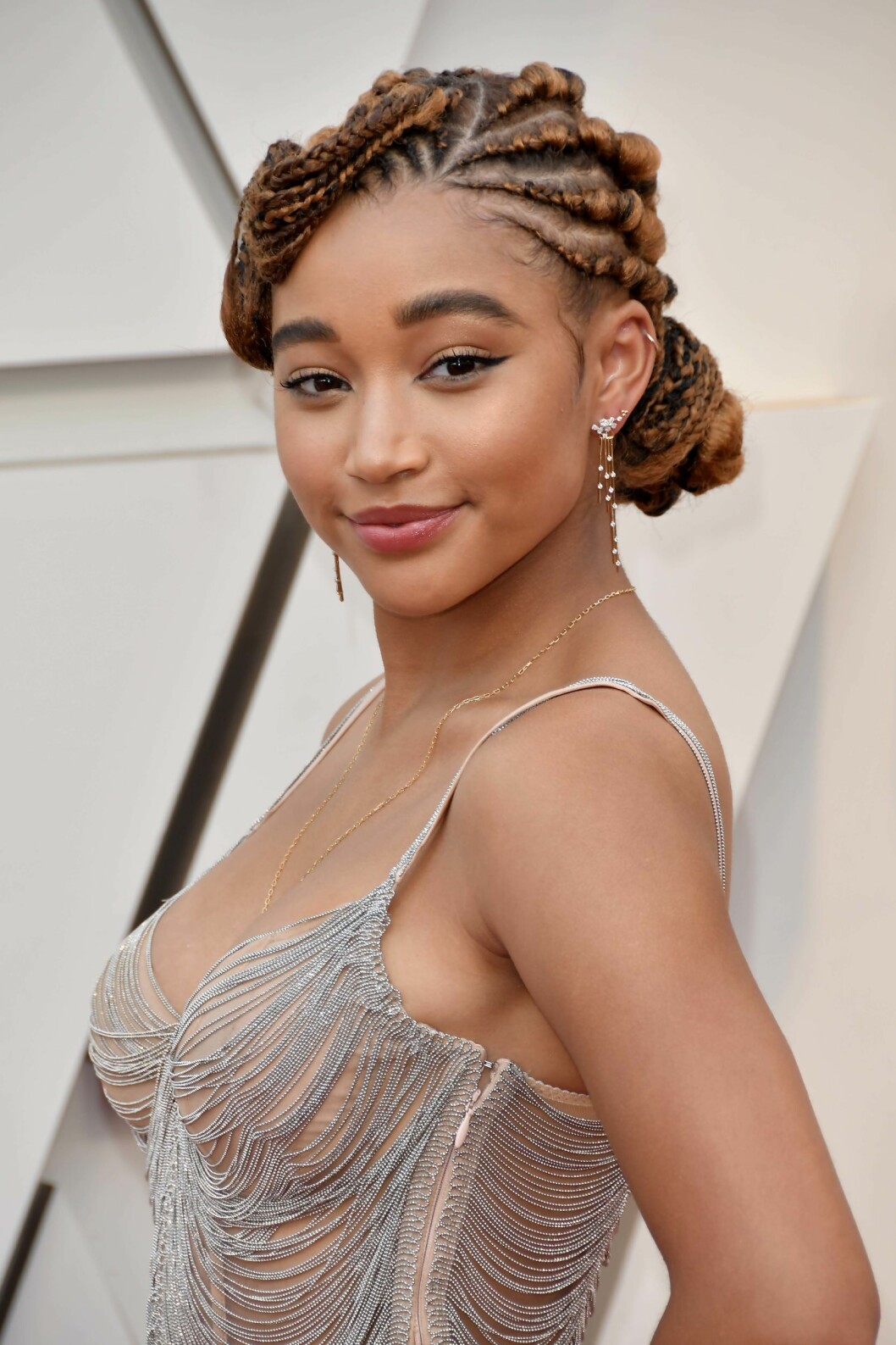 Amandla Stenberg med långa flätor i en låg knut.
