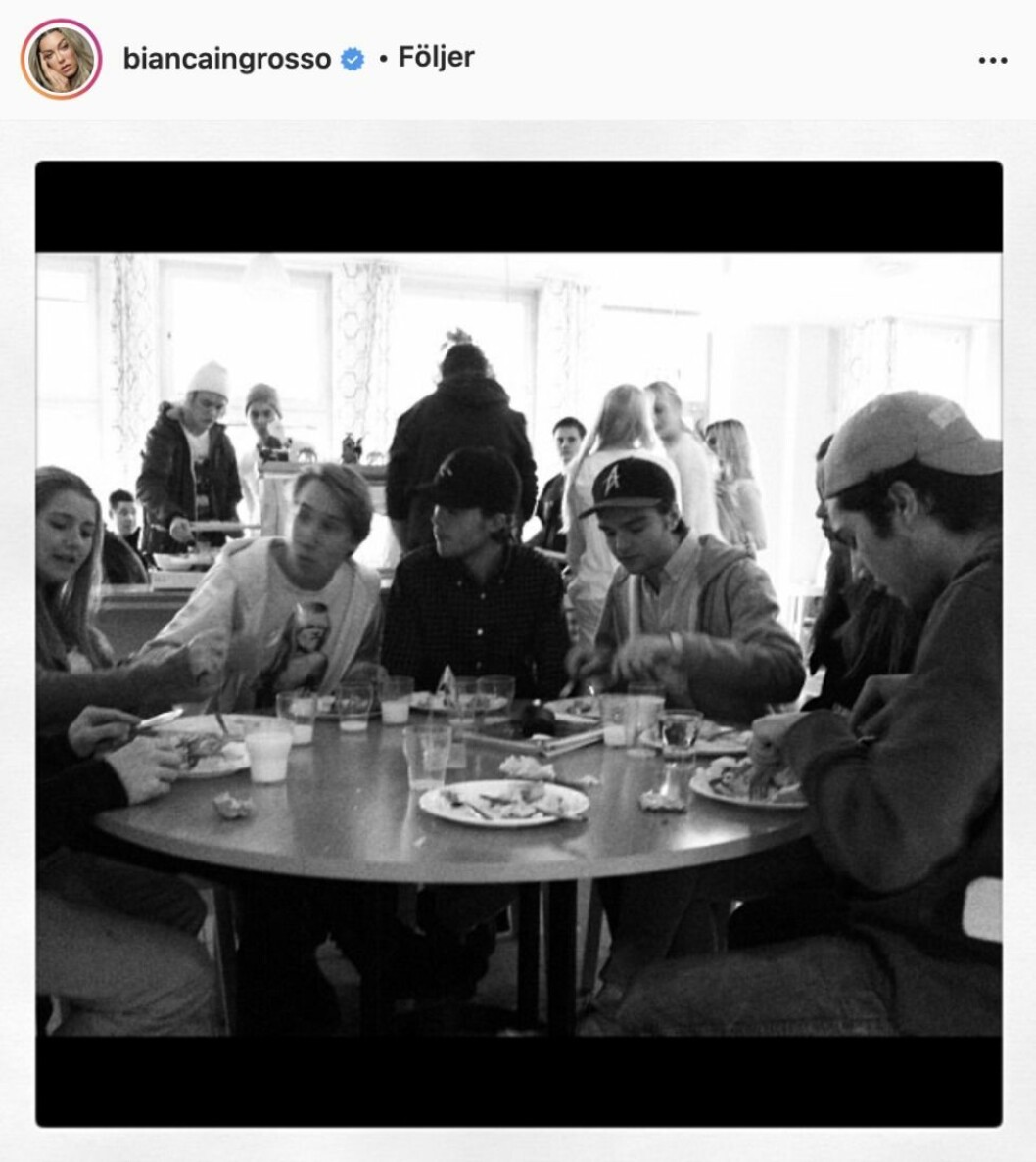 En svartvitbild med ungdomar som sitter runt ett bord och äter