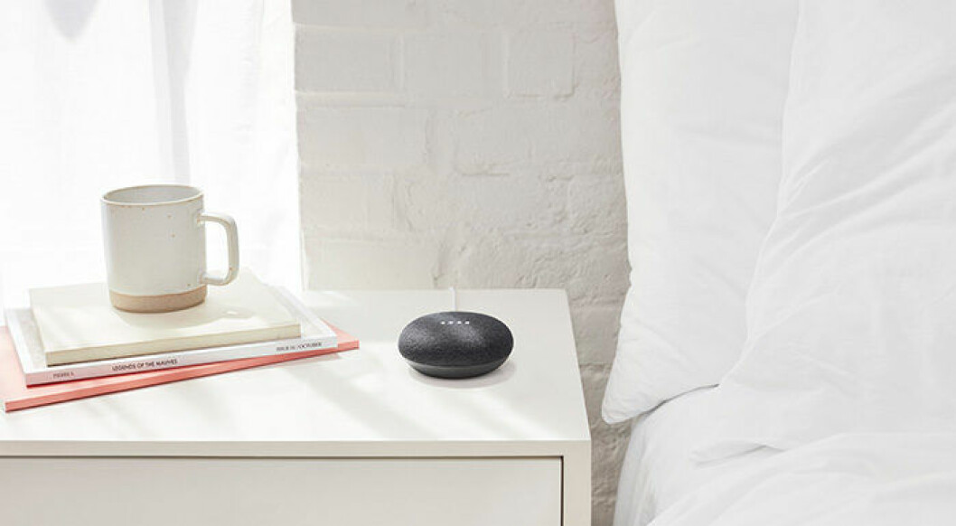 En bild på Google Home Mini på ett sängbord i ett sovrum. 