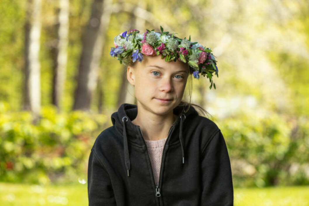 Greta Thunberg i svart munkjacka och blomsterkrans i håret