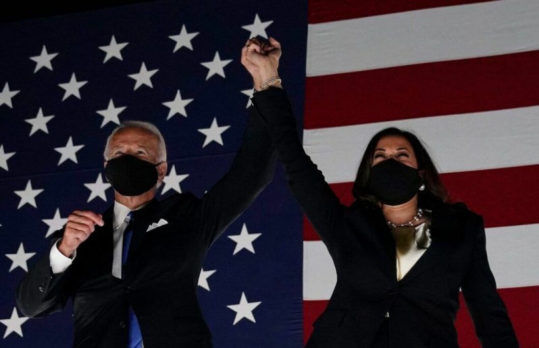 Joe Biden och Kamala Harris har ansiktsmask och sträcker upp händerna i luften