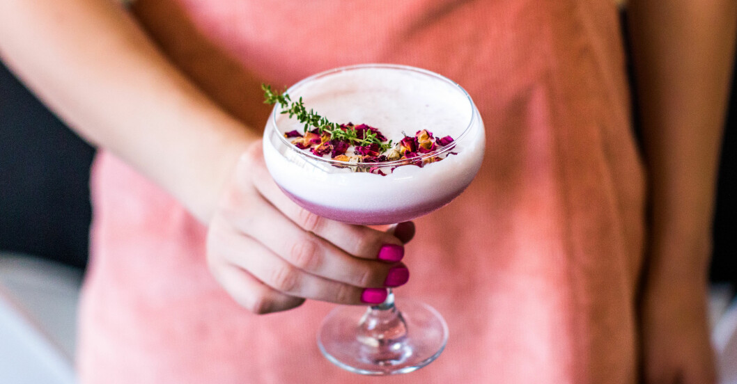 kvinna håller i lila drink med skum och blommor