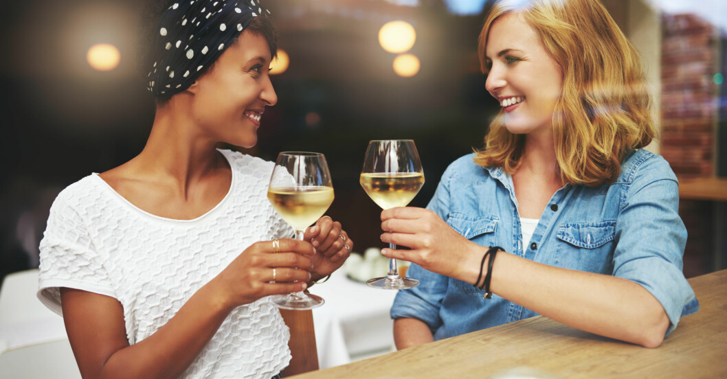 Tjejer skålar med vitt vin