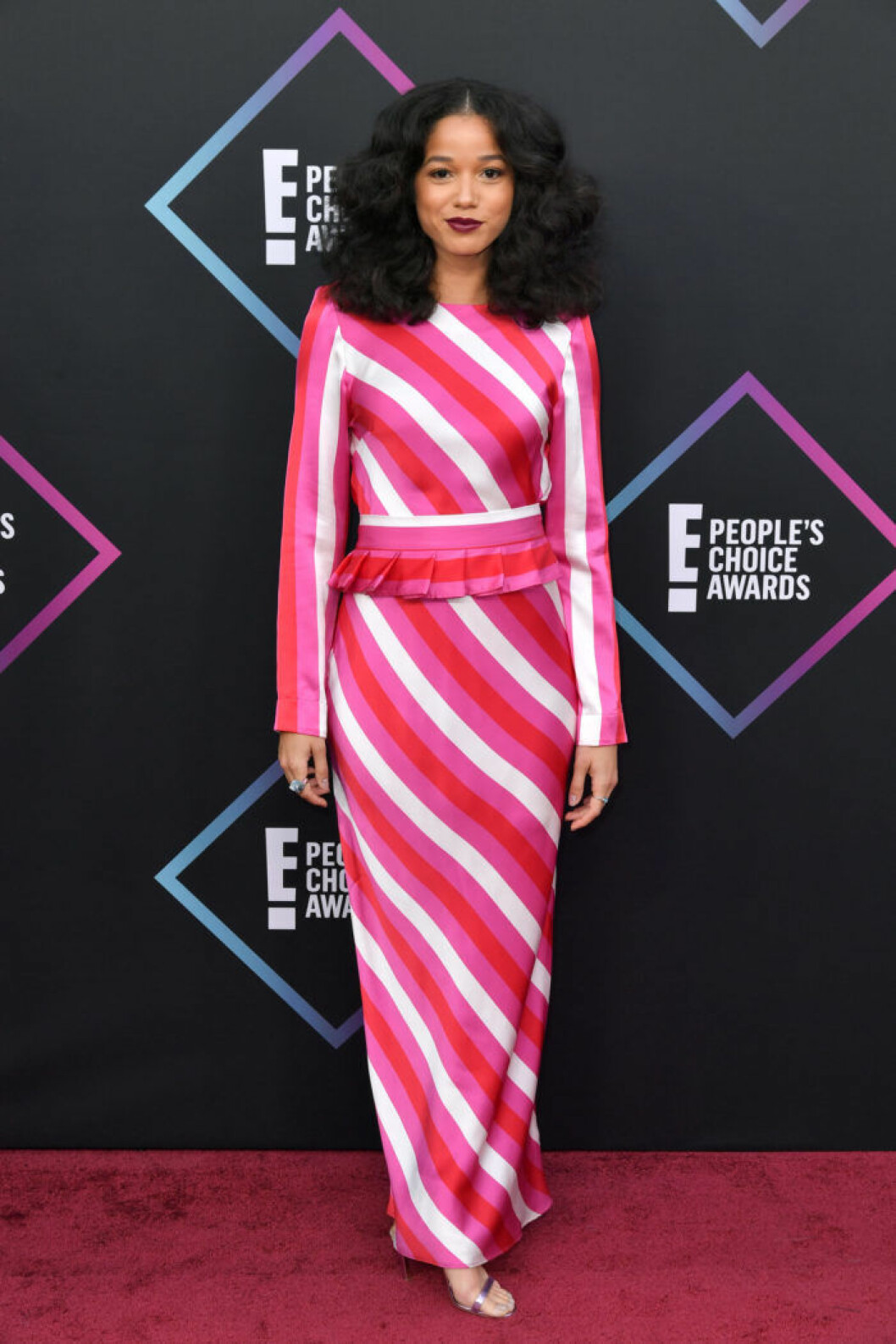 Skådespelaren Alisha Wainwright i en randig långklänning i rosa och rött. Foto: IBL Alisha Wainwright på People's Choice Awards 2018