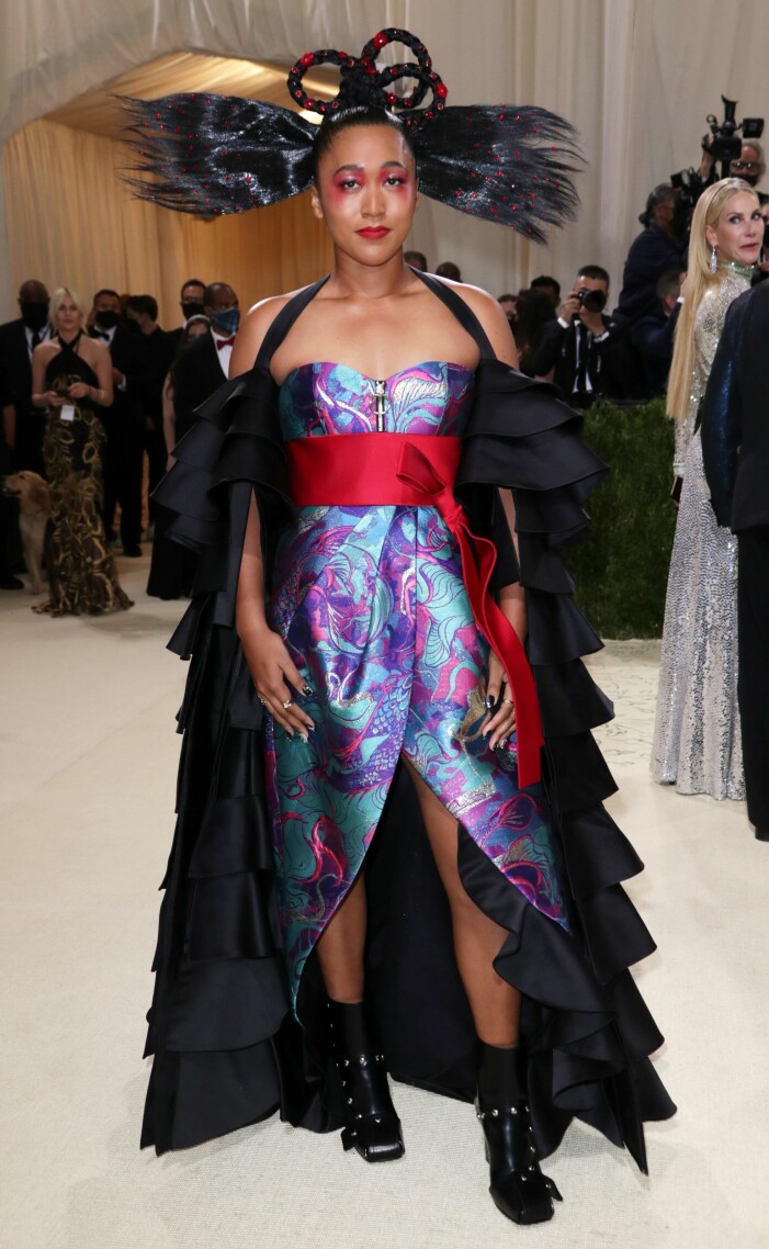 Naomi Osaka valde att slå samman både sitt japanska och haitiska arv i en kreation av Louis Vuitton. De veckade ärmarna osar karneval, och det röda bandet över kjolen påminner om bandet på en kimono. Naomi Osaka