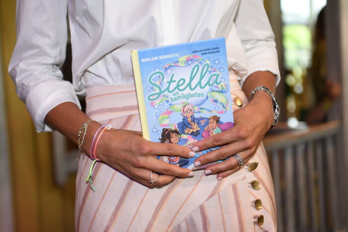 Prinsessan Madeline håller upp barnboken Stella och hemligheten.