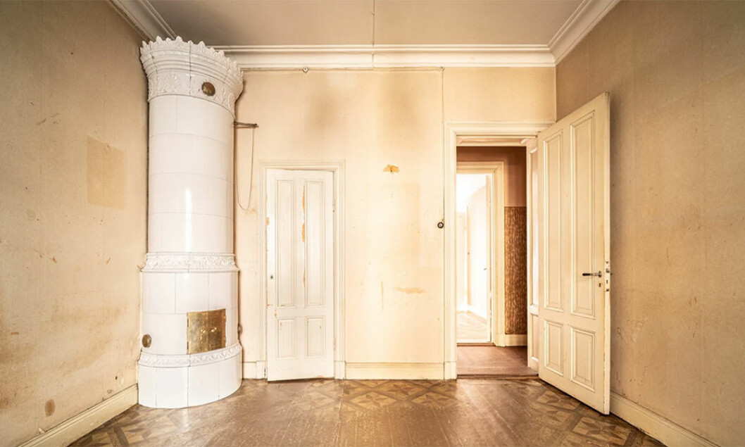 En av våningens tre kakelugnar. Foto: Richard Lundberg för Fastighetsbyrån/mäklare: Anna Johansson Vit rund kakelugn i sekelskifteslägenhet som stått tom