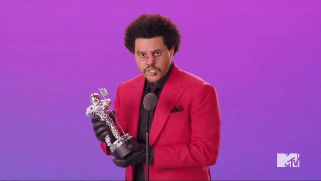 The Weeknd håller i ett pris och har röd kavaj på sig