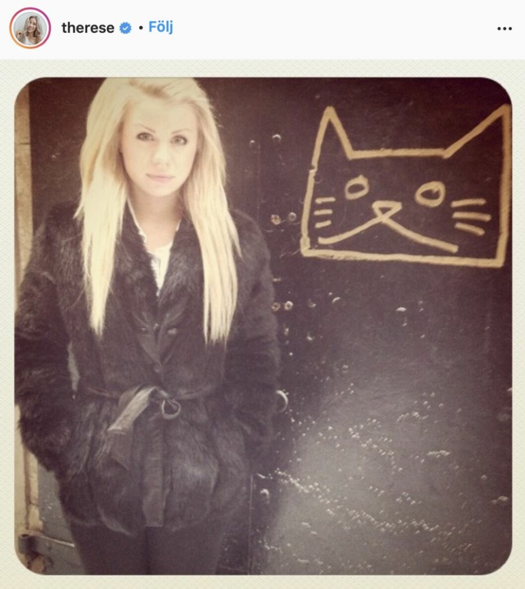 Therese Lindgren står framför en svart vägg med en målad katt på