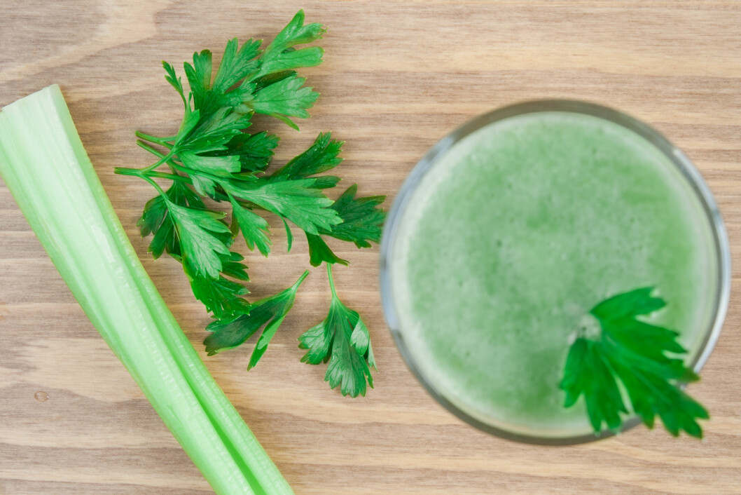 Healthy green smoothie with celery and parsley on wooden table.